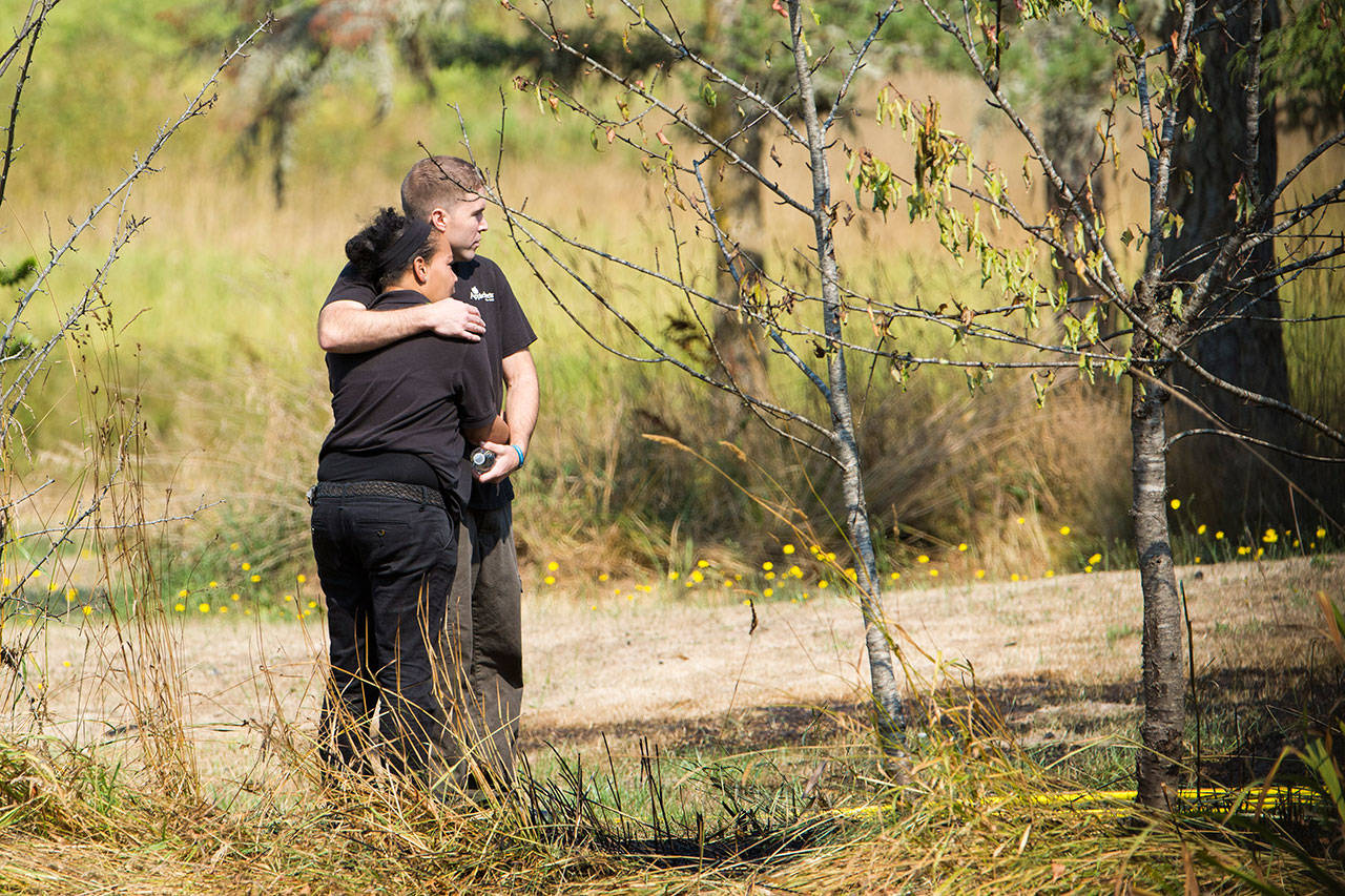 Joseph Bell embraces his wife Destinee McFarlane as they watch their home at the corner of Blue Mountain Road and School House Lane burn Tuesday afternoon. Both were at work when the fire started. (Jesse Major/Peninsula Daily News)