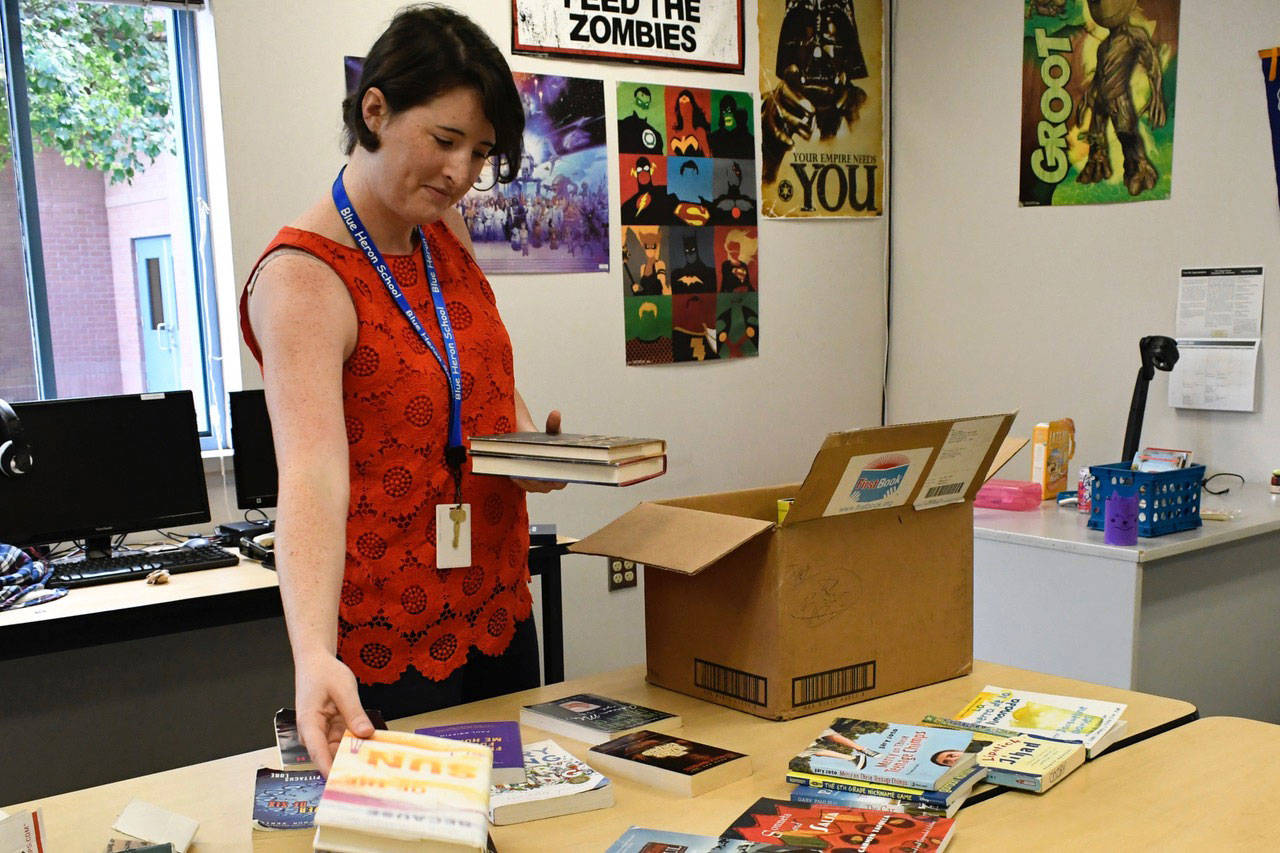 Becca Gimlett, a Blue Heron Middle School reading teacher for sixth through eighth grades, unpacks boxes of books she brought from her previous position in Oregon. (Jeannie McMacken/Peninsula Daily News)