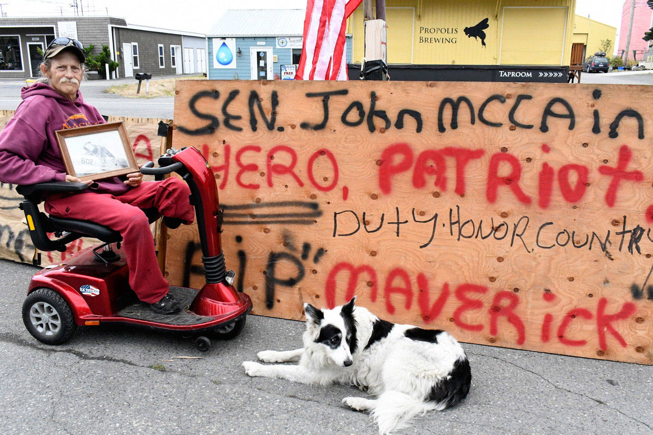 Veteran Timothy Morgan of Irondale pays his respects to the late Sen. John McCain (R-Ariz.) with a display on Sims Way in Port Townsend. (Jeannie McMacken/Peninsula Daily News)