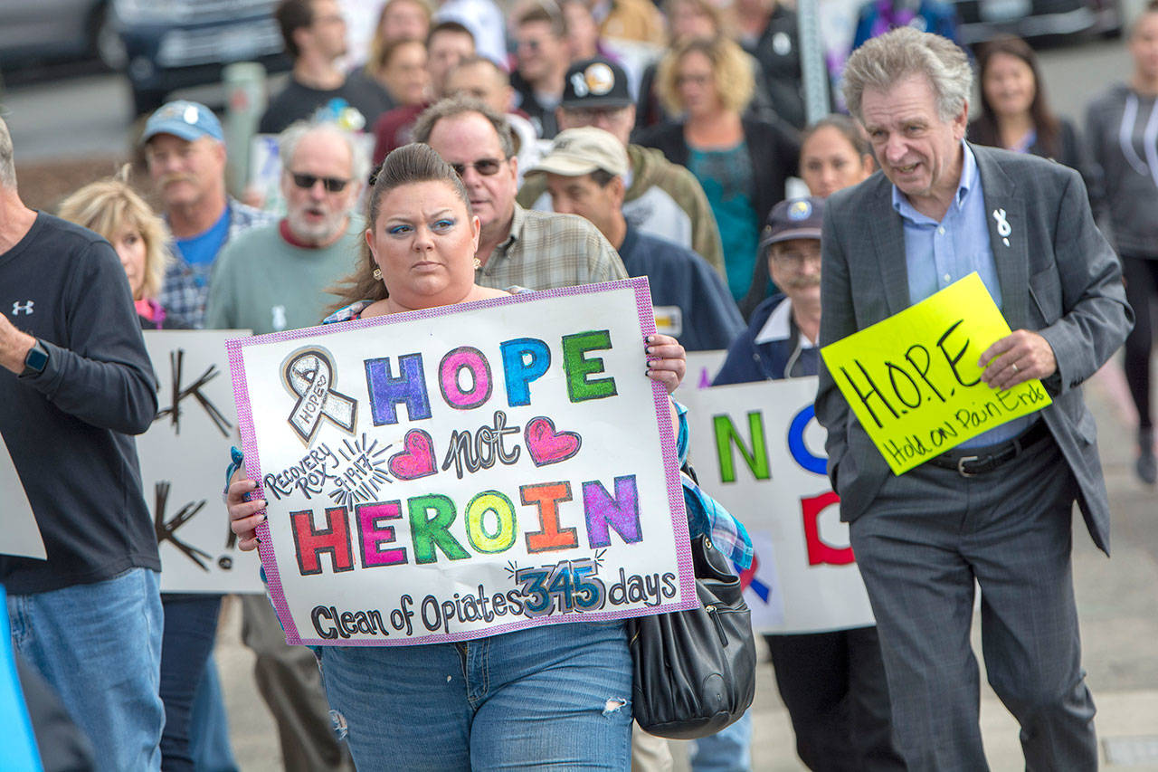 Miranda Beck of Port Angeles holds a sign as the International Overdose Awareness Day walk makes its way toward the Port Angeles City Pier on Friday. (Jesse Major/Peninsula Daily News)