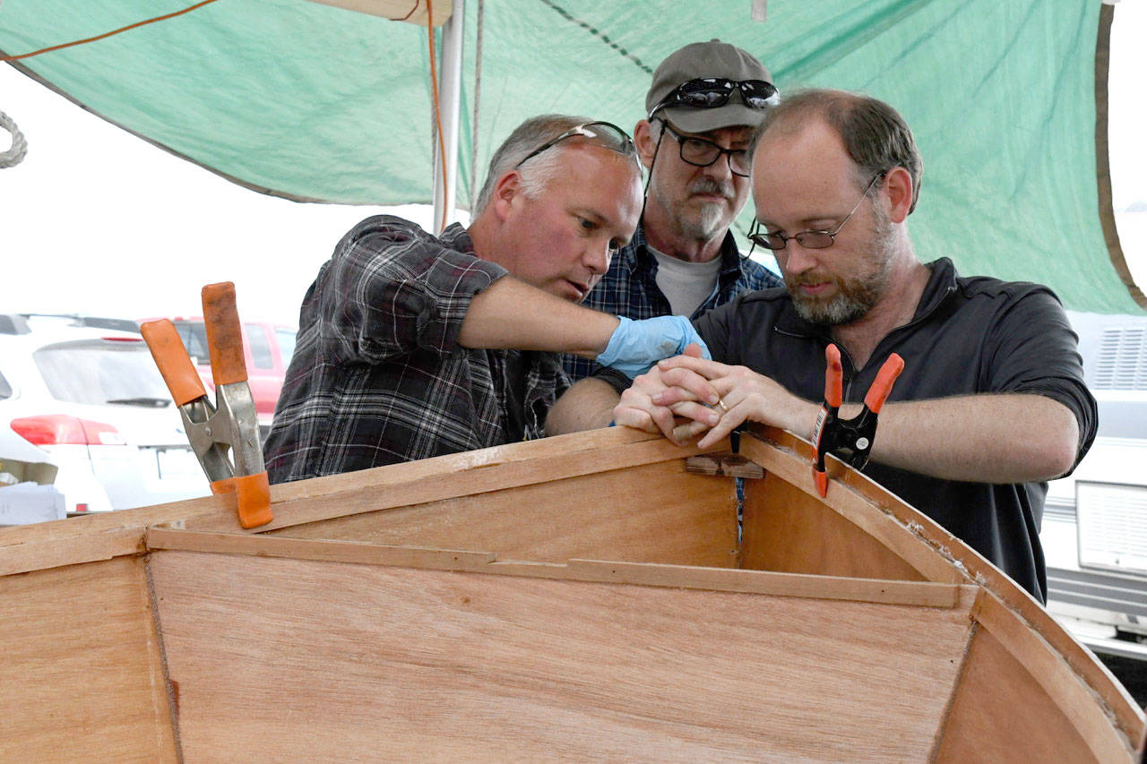 Members of Team Critical Path work on their entry, a 9-foot-by-4-foot Glen L Tubby Tug, for the Edensaw Boatbuilding Challenge at the Wooden Boat Festival. Team member Bob Lee said their boat is a mini-tugboat that’s popular with kids. The men will build a cabin, and attach an electric motor. When completed it will hold up to 300 pounds. The team includes, from left, Ron Doll, Christopher Street and Jonathan Lee. (Jeannie McMacken/Peninsula Daily News)