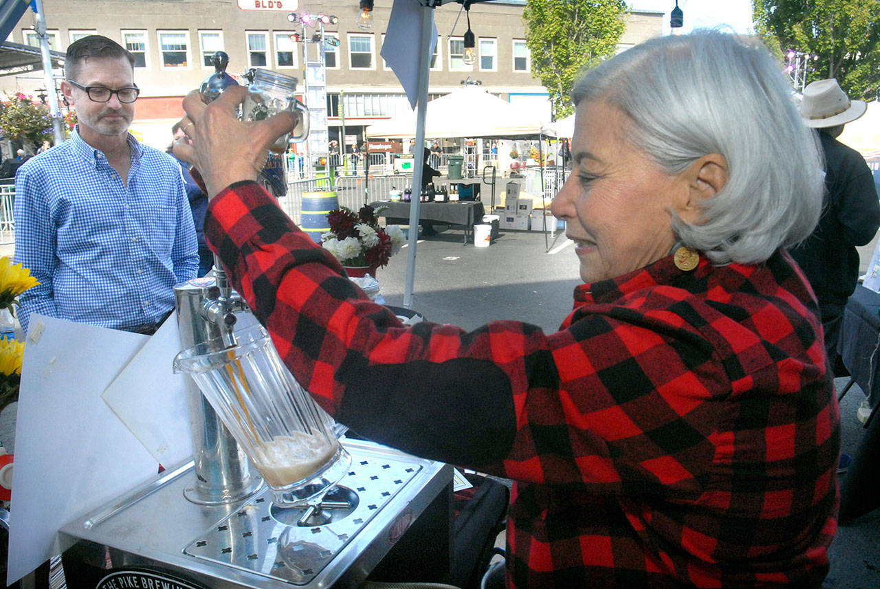Rose Ann Finkel of the Seattle-based Pike Brewing Co., right, pours beer into a pitcher before serving a sample glass to Michael Nielsen of Seattle during last year’s featured beer and wine tasting, part of the Arts & Draughts Festival in downtown Port Angeles. (Keith Thorpe/Peninsula Daily News)