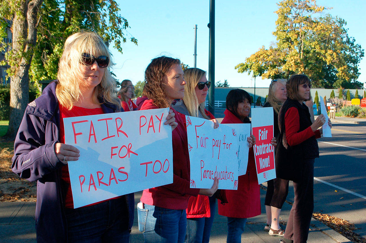 Paraeducators from Helen Haller Elementary School, from left, Veronica Catelli, Stephanie Dormer, Sarah Sullivan and Monica Gonzalez gather along the corner of North Sequim Avenue and West Fir Street with other paraeducators to lobby for equitable salaries Monday. (Erin Hawkins/Olympic Peninsula News Group)