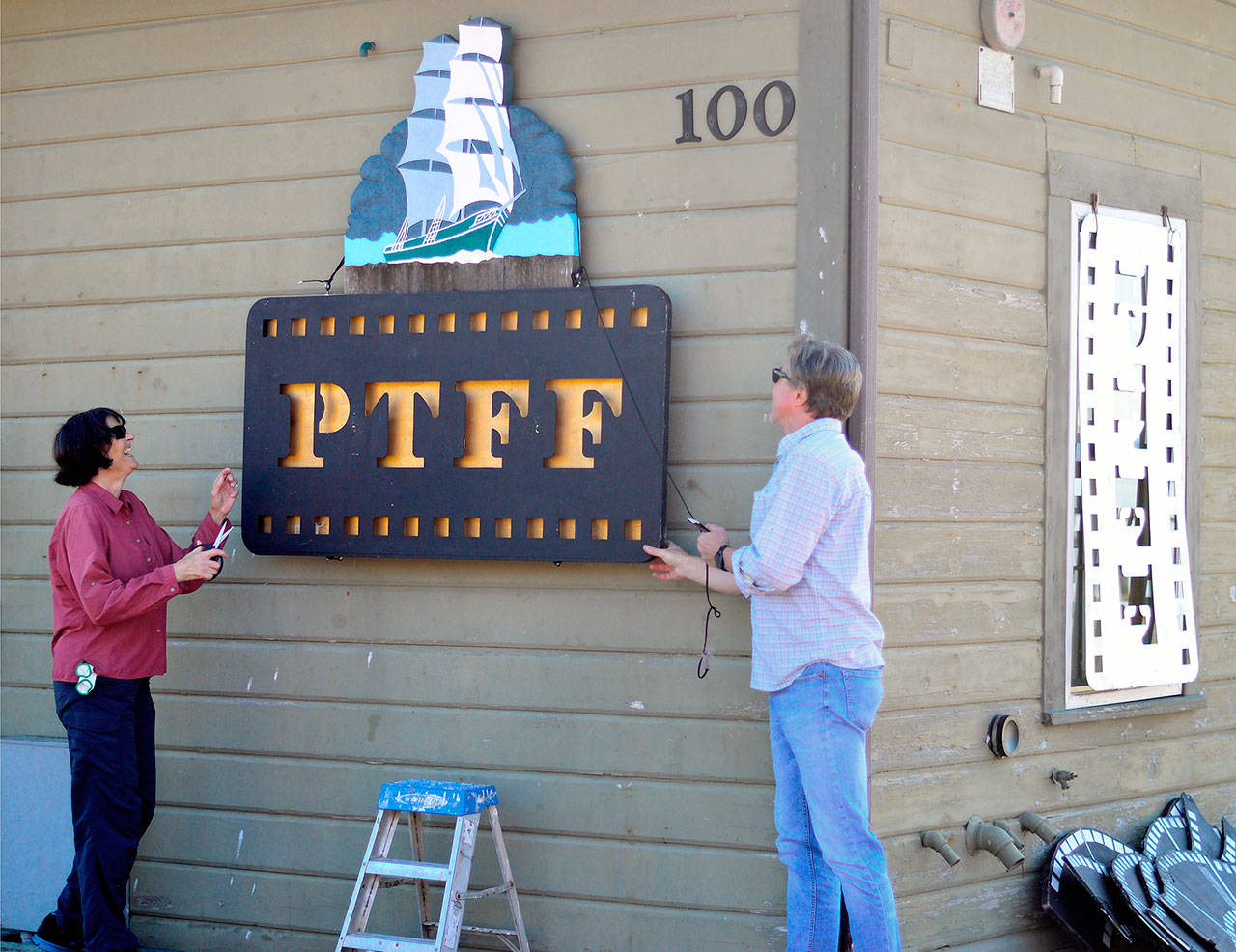 Port Townsend Film Festival volunteers Jayne Marek and Rich Stewart rig up the sign for the Festival Bar on the Dock on Wednesday morning. (Diane Urbani de la Paz/for Peninsula Daily News)