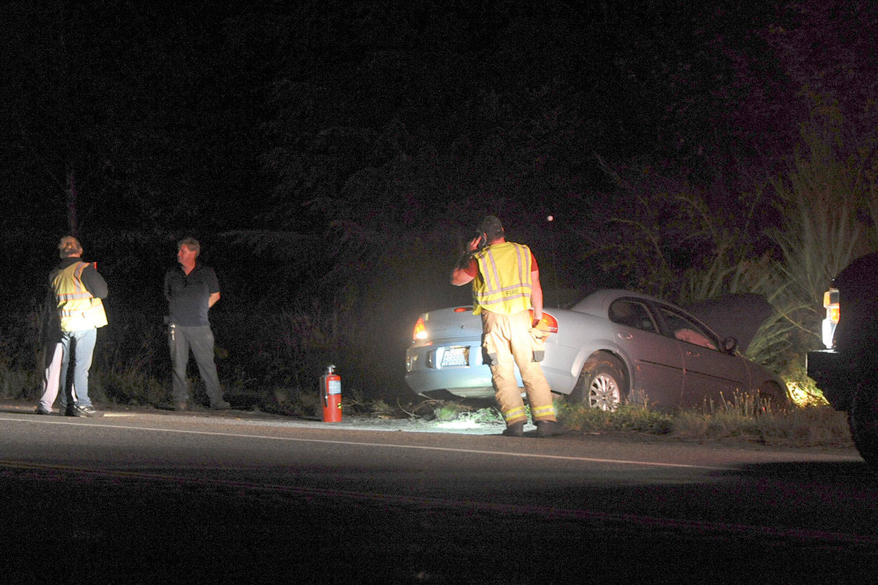 Firemen check a vehicle off the roadway of U.S. Highway 101 at milepost 200 at 10:15 p.m. Wednesday. (Lonnie Archibald/for Peninsula Daily News)