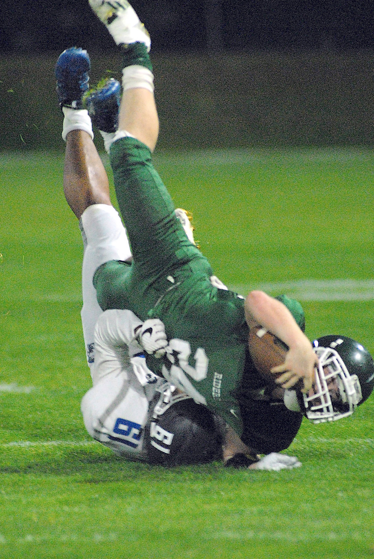 Keith Thorpe/Peninsula Daily News Port Angele’s Trevor Shumway, front, is upended by Olympic’s Jessie Brown during the first quarter of play on Friday night at Port Angeles Civic Field.