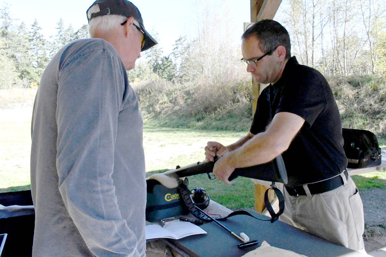 Mike Roth, range master at the Jefferson County Sportsmen Association range in Port Townsend helps Rick Kronquist of Marrowstone Island clean the carbon build up from his .50 caliber muzzleloader black powder rifle. (Jeannie McMacken/Peninsula Daily News)