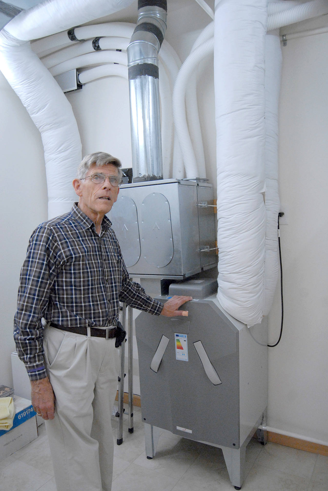 David Large describes the functions of a heat recovery ventilator that transfers warm or cool air trough his energy-efficient house. (Keith Thorpe/Peninsula Daily News)