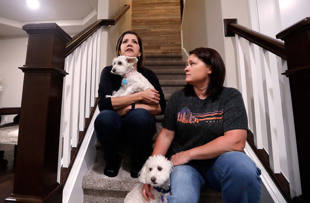 Las Vegas shooting survivor Chris Gilman, right, sits with her wife, Aliza Correa, and their two dogs at their home Sept. 24 in Bonney Lake. (Elaine Thompson/The Associated Press)