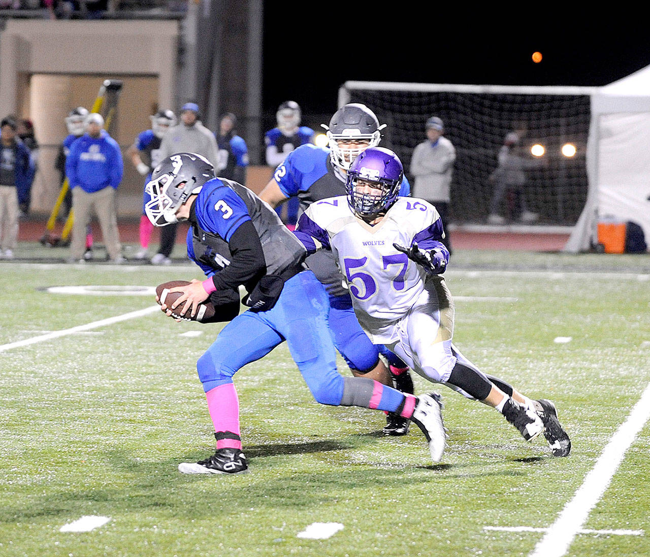 Sequim defensive end Austin Henning (57) tries to wrap up Olympic quarterback Ezekiel Gillick in the first half of Sequim’s 28-9 league victory on Friday night. (Michael Dashiel/Olympic Peninsula News Group)