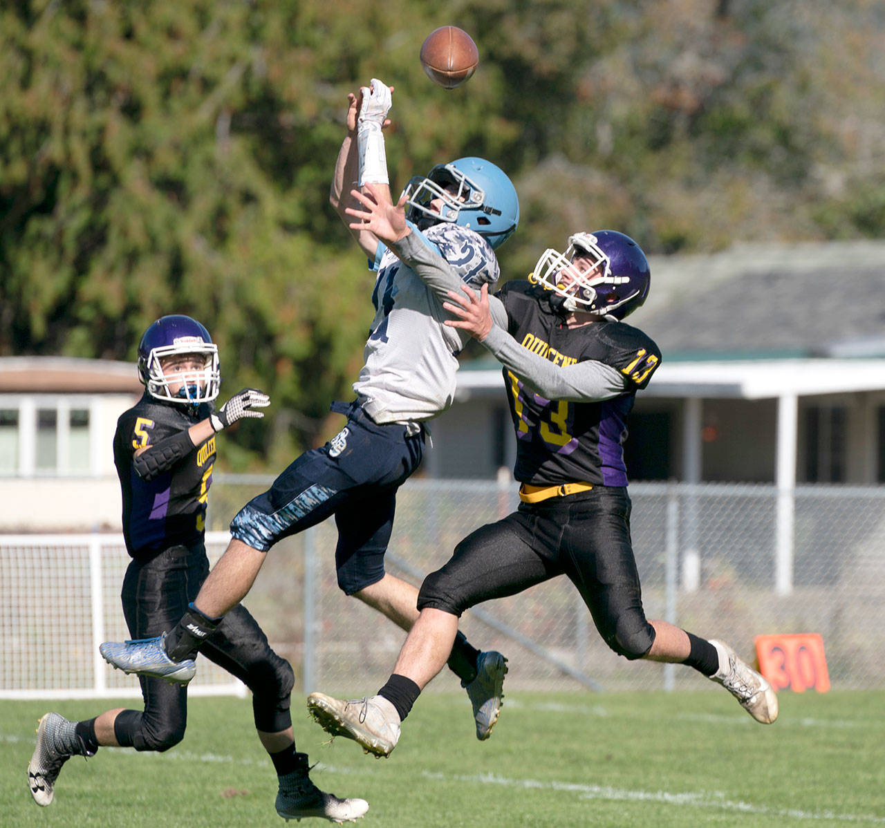 Quilcene’s Olin Reynolds breaks up a pass intended for Rainier Christian’s Landen Bruce during a game in Quilcene on Saturday. Ranger Isaac Dugdale (5) is poised to assist in the play. (Steve Mullensky /for Peninsula Daily News)