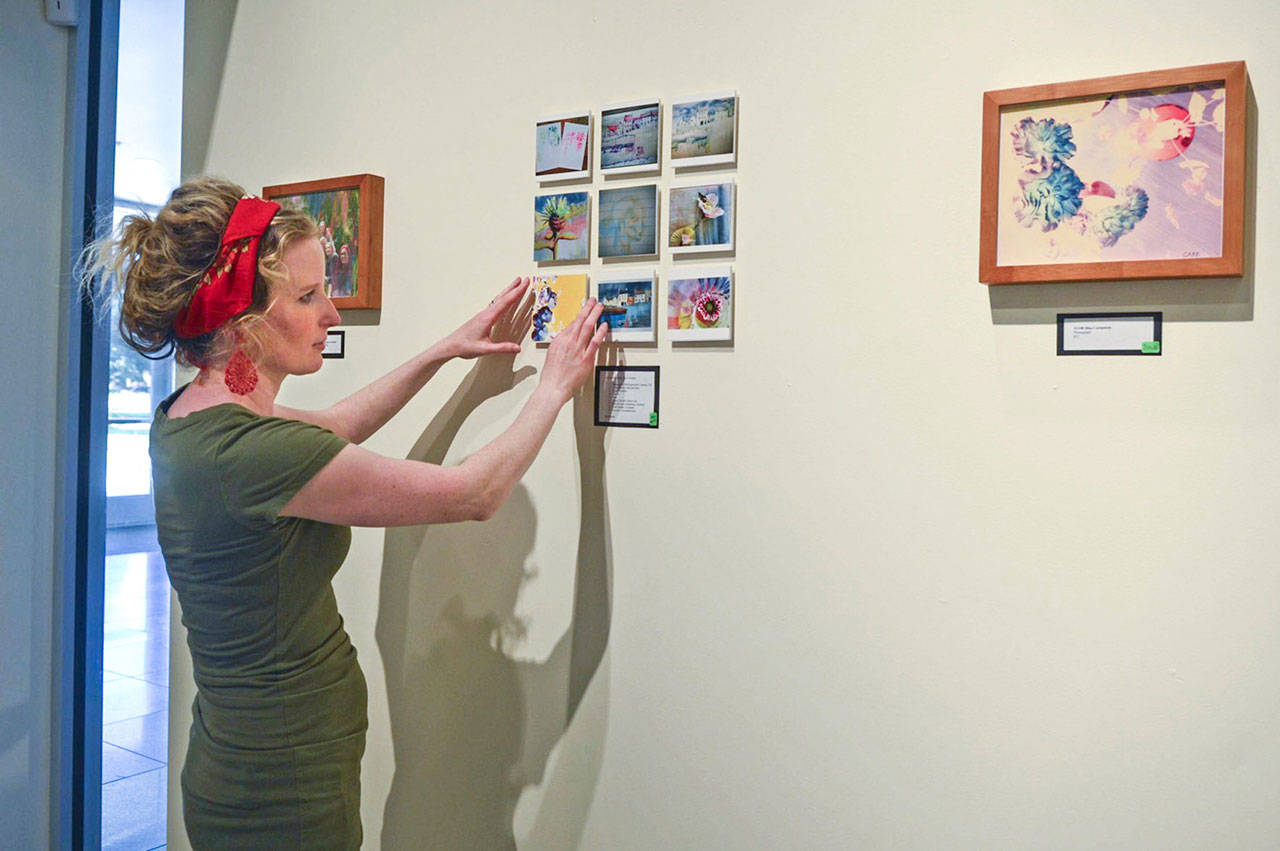 Anne-Marie Carr, 41, straightens out some of her paintings displayed Sept. 28 at the Lower Columbia College Rose Center for the Arts in Longview. (Katie Fairbanks/The Daily News via AP)