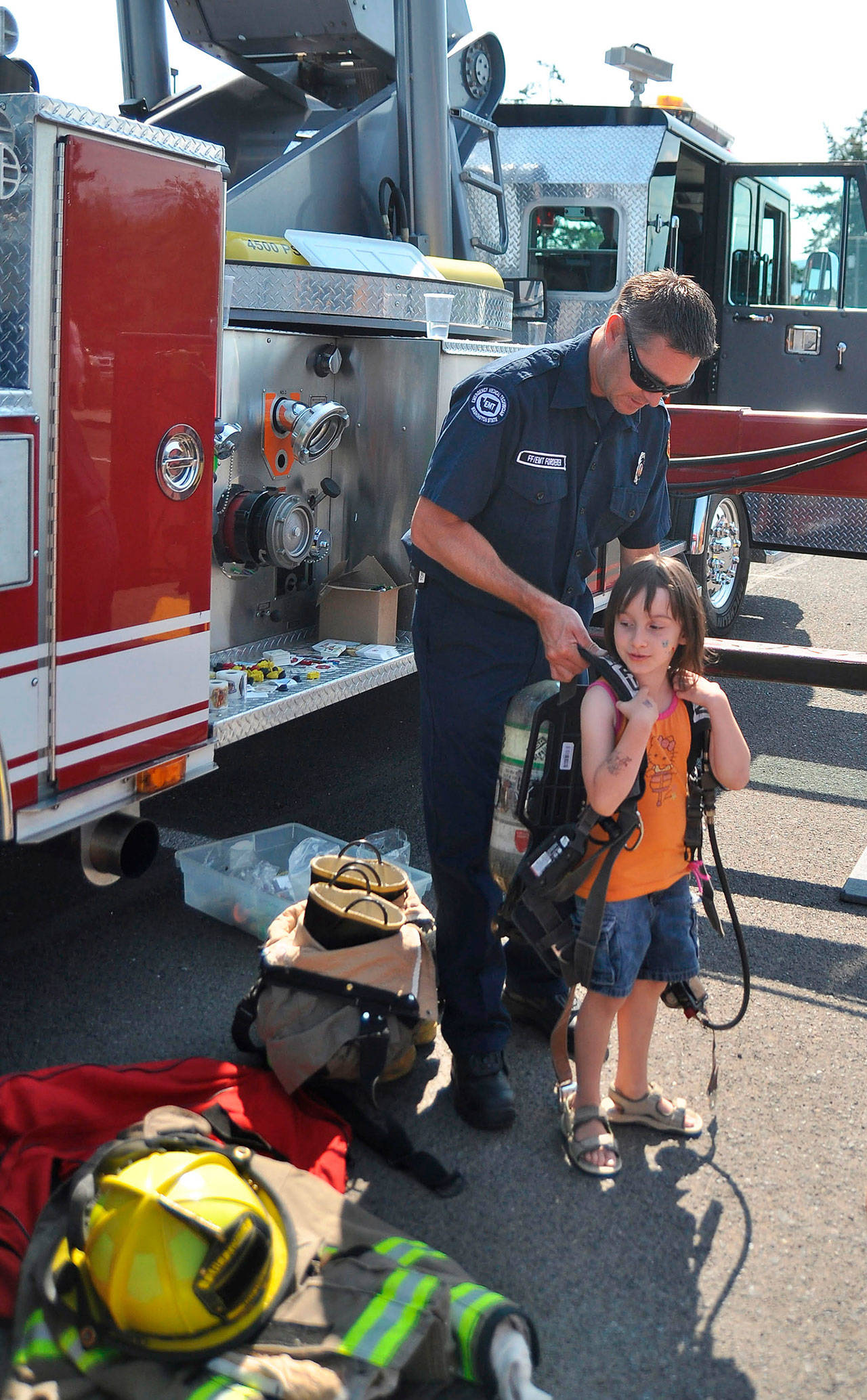 Clallam County Fire District No. 3 firefighter/EMT Lee Forderer, left, helps Lindsey Anderson, try on some firefighting equipment in 2014. (Mike Dashiell/Olympic Peninsula News Group)