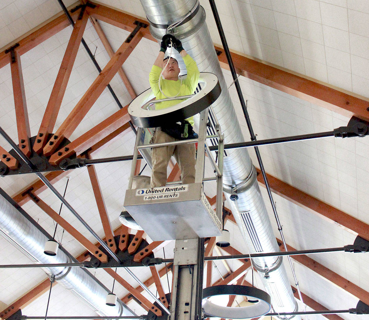 Lead electrician Vladimir Romanov of Lumenal Lighting replaces outdated lighting fixtures with energy efficient LED lightbulbs in October in the Nora Porter Commons Building at Fort Worden. (Megan Claflin)