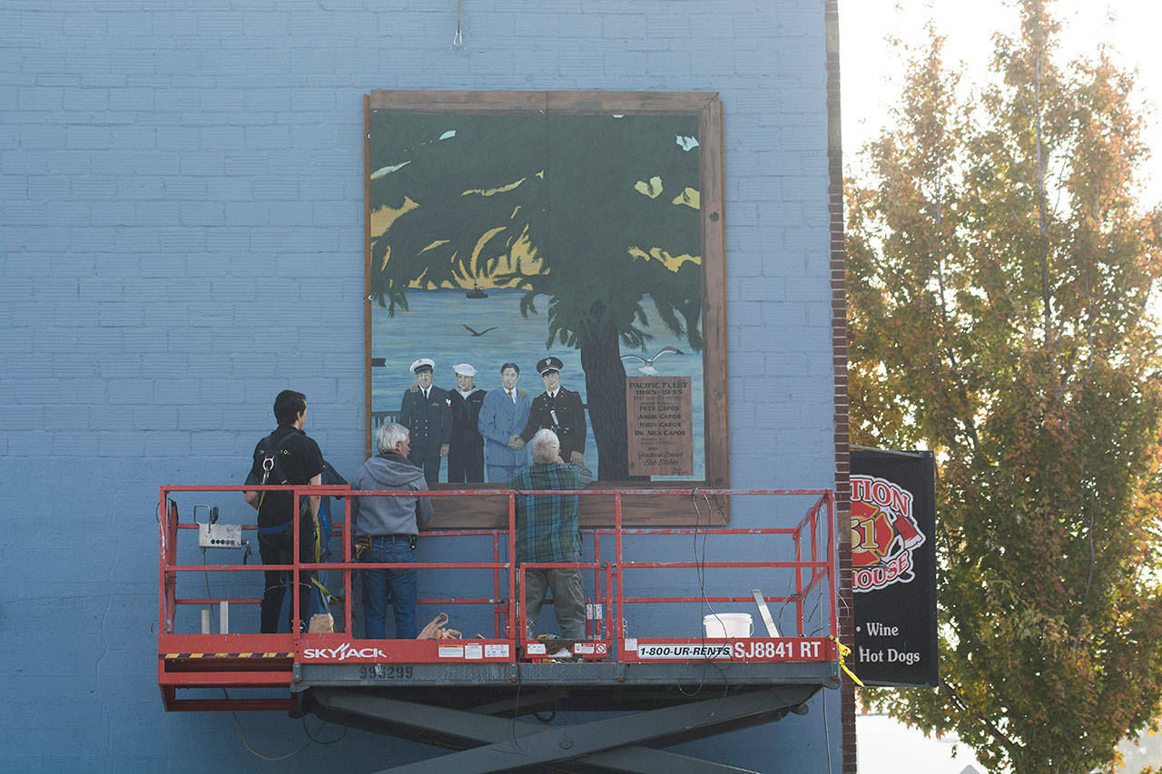 Crews mount a panel of the Pacific Fleet mural on the west side of the former Station 51 Taphouse in Port Angeles on Monday afternoon. (Jesse Major/Peninsula Daily News)