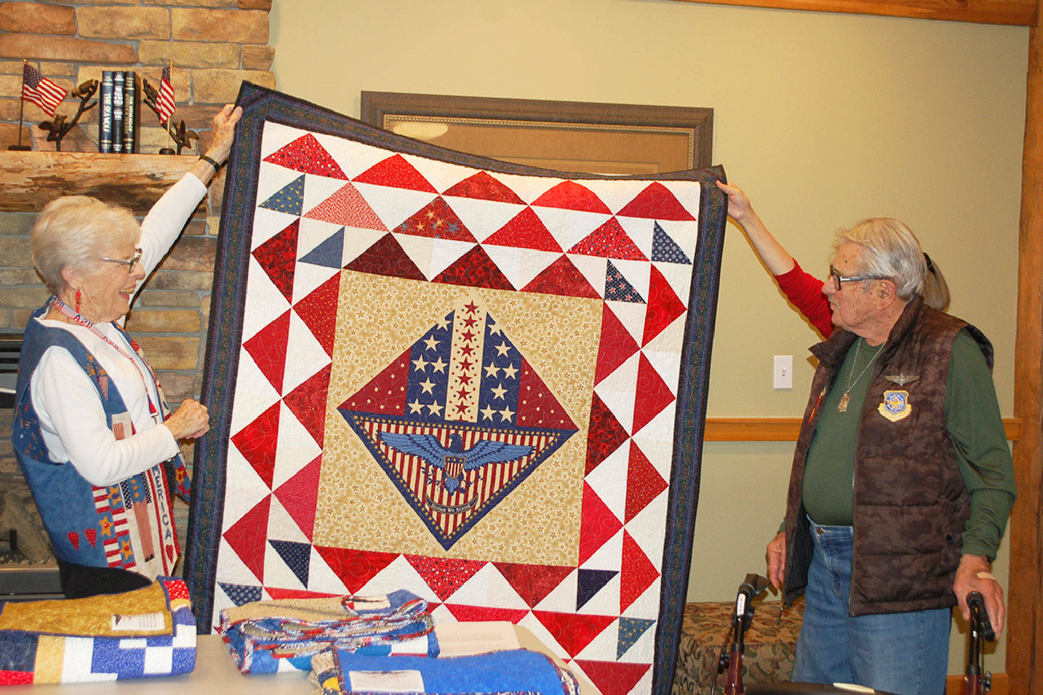 Barbara Hughes, a member of the quilting group “Grateful Grannies,” presents a quilt to Monte Mogi, a local Vietnam War veteran who served in the U.S. Air Force as a flight engineer, at the Lodge at Sherwood Village. Erin Hawkins/Olympic Peninsula News Group