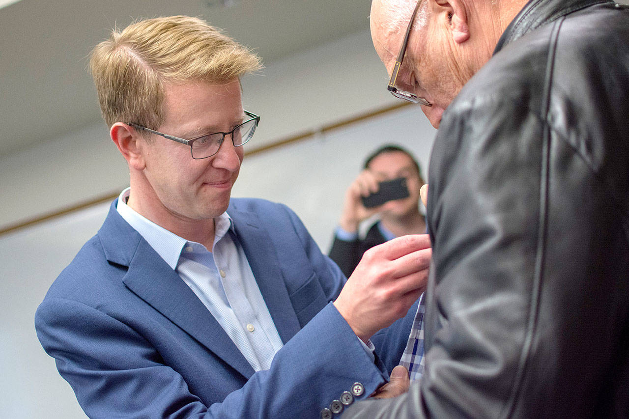U.S. Rep. Derek Kilmer puts a pin on a veterans jacket during a pinning ceremony for Vietnam War era veterans in Port Ludlow Thursday evening. (Jesse Major/Peninsula Daily News)