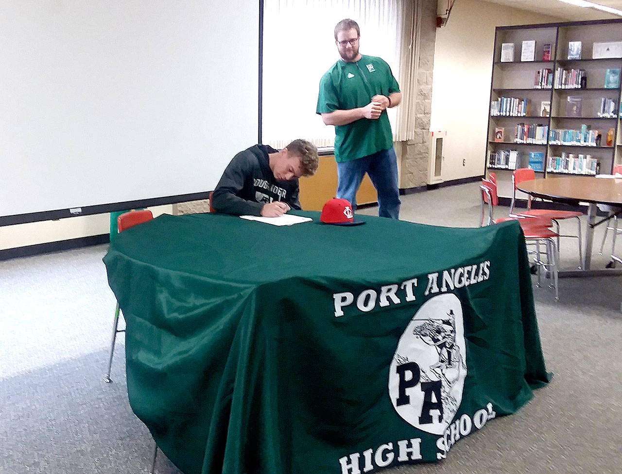 Port Angeles Roughrider baseball coach Karl Myers watches as his star catcher, Joel Wood, signs a letter of intent to attend Lower Columbia College in Longview at Port Angeles High School on Saturday. (Pierre LaBossiere/Peninsula Daily News)
