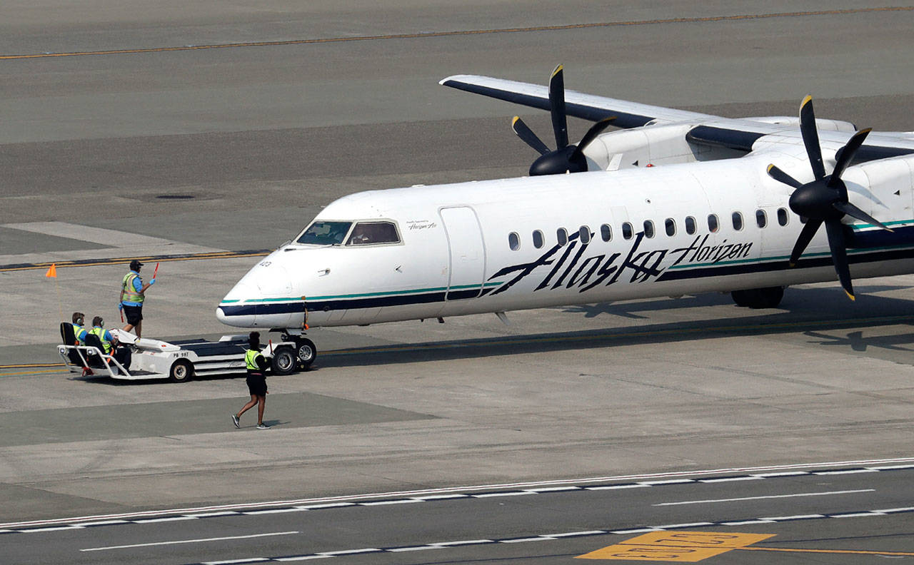 In this Aug. 13 file photo, a Horizon Air Q400 turboprop airplane, part of Alaska Air Group, is moved into position by airport workers at Seattle-Tacoma International Airport in SeaTac. The plane is the same model of aircraft stolen from the airport by an airline ground agent which later crashed into crashed into a small island in the Puget Sound, killing the man. (The Associated Press)