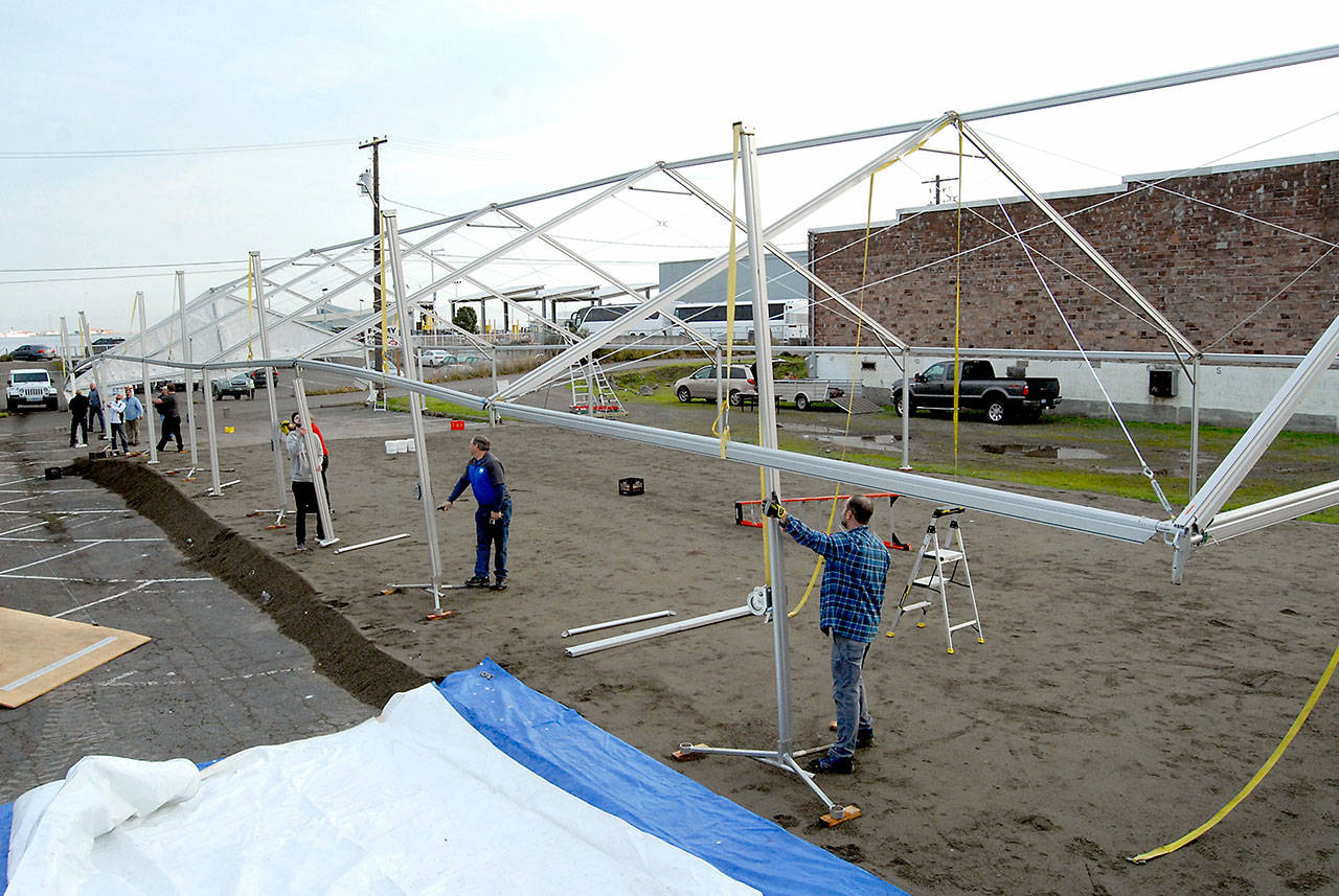 A crew erects a tent Tuesday that will cover a temporary skating rink in a parking lot on the 100 block of West Front Street in Port Angeles. (Keith Thorpe/Peninsula Daily News)
