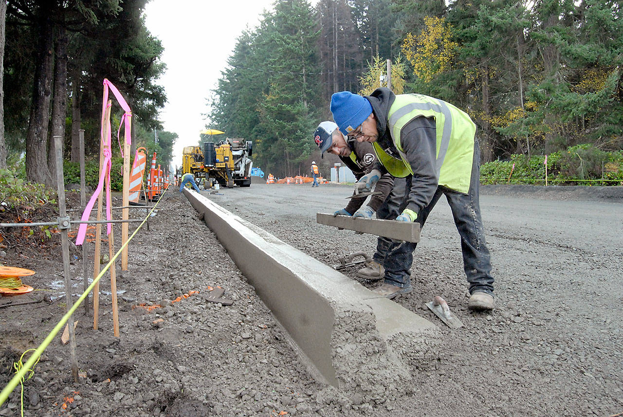 Jaime Ramirez, left, and Louis Vazquez, both of Wilson Concrete Construction Inc., smooth a freshly-poured section of concrete curbing Wednesday as part of a project to rebuild a section of West 10th Street between I and N streets in Port Angeles. (Keith Thorpe/Peninsula Daily News)