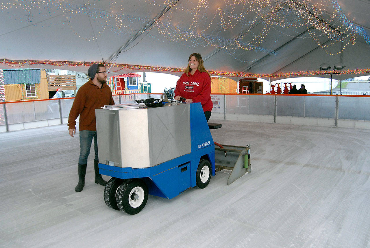 Leslie Robertson of Port Angeles, right, receives instruction Wednesday on how to operate an ice resurfacing machine from D.J. Longnecker of Torrance, Calif.-based Ice-America on the temporary ice skating rink set up on West Front Street in downtown Port Angeles. (Keith Thorpe/Peninsula Daily News)