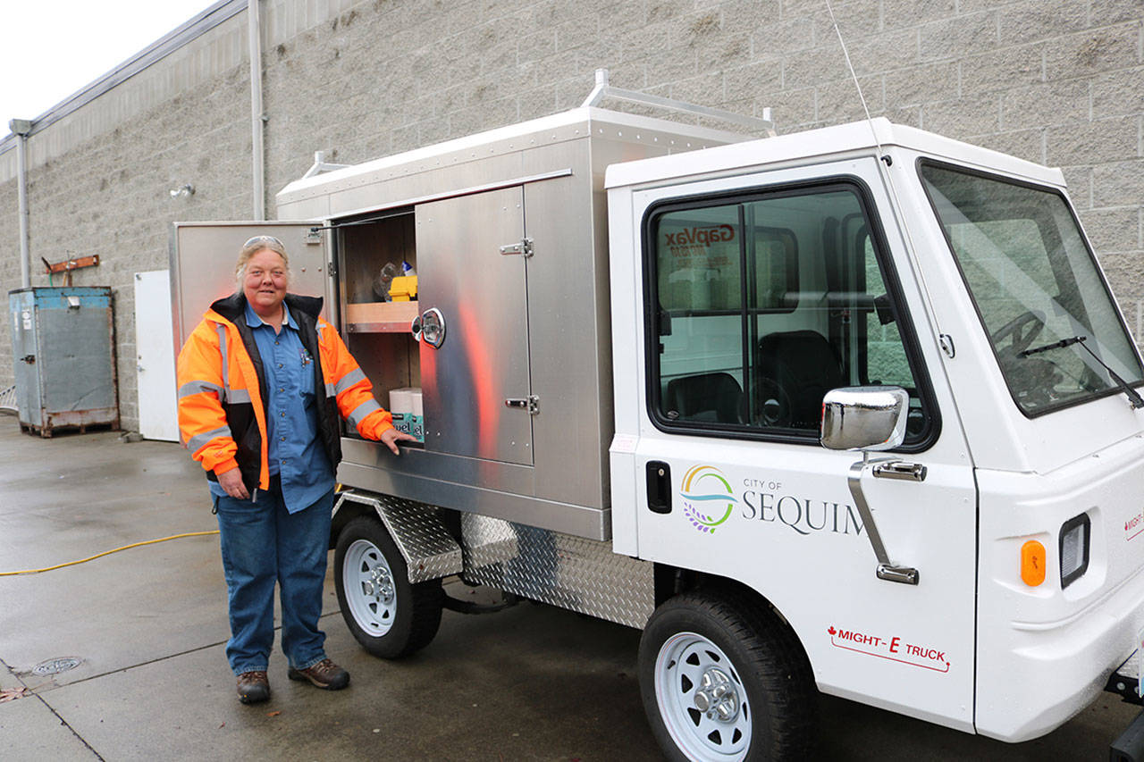 City of Sequim Public Works maintenance worker Cindy Budd stands by the citys new Might-E-Truck, an electric vehicle that helps the city reduce fuel costs and emissions.