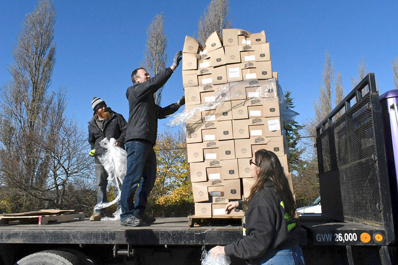 Arrow Lumber Vice President and Manager Cadian Hendricks, center, unwraps the final pallet of turkeys for the Port Townsend Food Bank. On hand to help were employees Maggie Kelleher and Willie Rogers. (Jeannie McMacken/Peninsula Daily News)