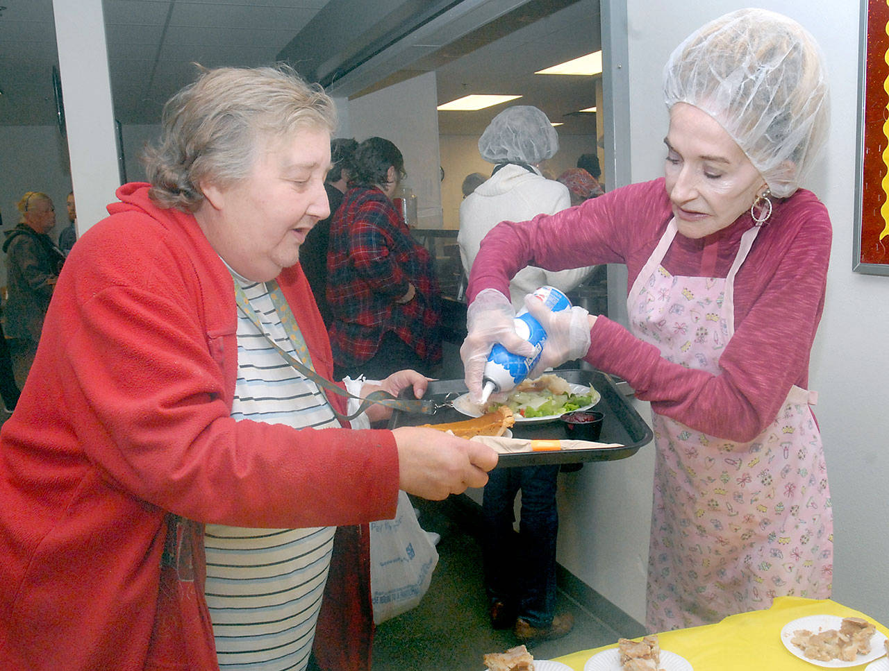 Christine Taylor of Port Angeles, left, watches as Ann Powers of Joyce adds whipped cream to a piece of pumpkin pie during Wednesday’s community lunch at the Salvation Army’s center in Port Angeles. Organizers expected about 200 people to take part in the free meal on the day before Thanksgiving. (Keith Thorpe/Peninsula Daily News)