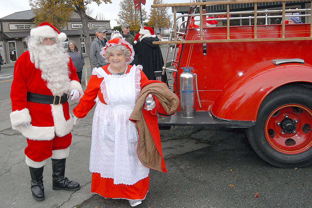 Keith Thorpe/Peninsula Daily News Santa Claus and Mrs. Claus (portrayed by Joe Borden and his wife, Tawana Borden, arrive by fire truck at Centennial Place in downtown Sequim during festivites on Saturday to kick off the holiday season. Holiday-goers were serenaded with Christmas music and youngsters were given the opportunity to reveal their gift wishes to the Jolly Old Elf.