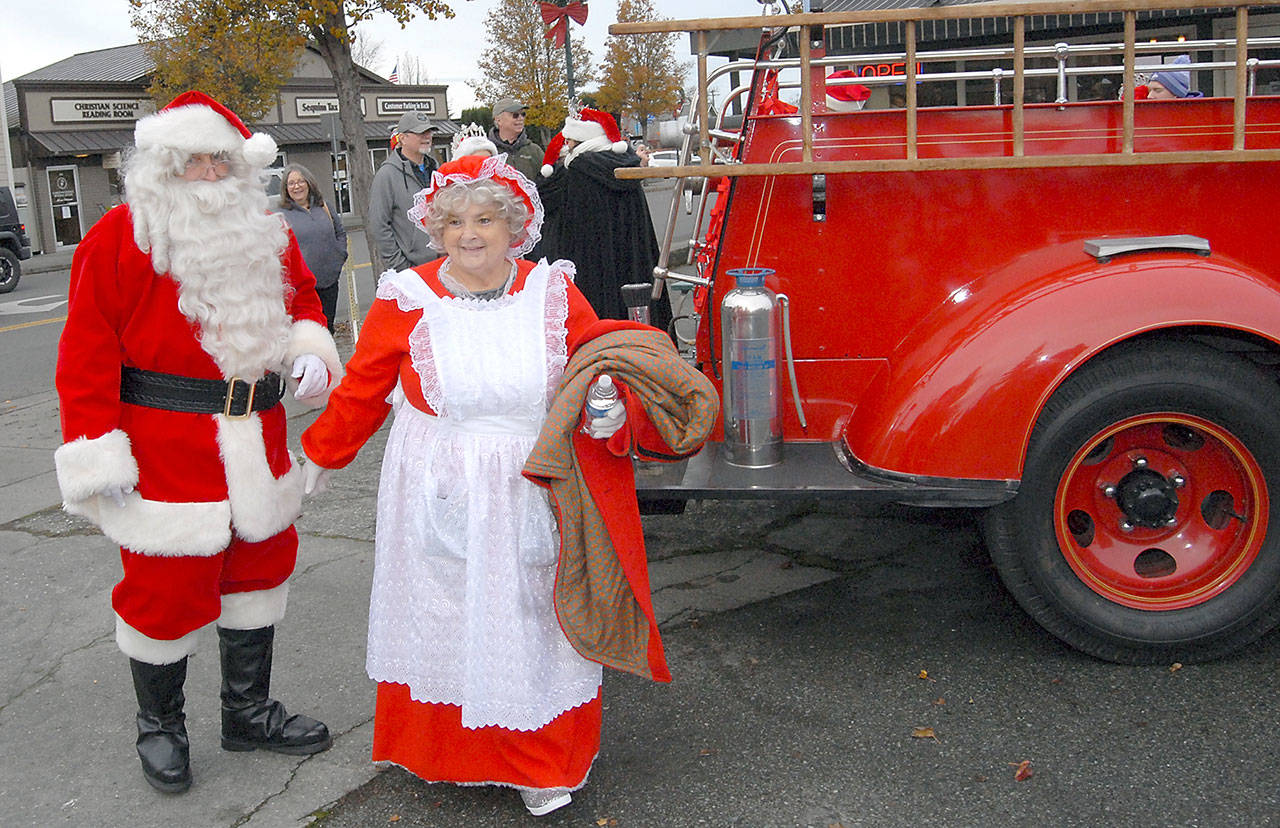 Santa Claus and Mrs. Claus (portrayed by Joe Borden and his wife, Tawana Borden, arrive by fire truck at Centennial Place in downtown Sequim during festivites on Saturday to kick off the holiday season. Holiday-goers were serenaded with Christmas music and youngsters were given the opportunity to reveal their gift wishes to the Jolly Old Elf. Port Angeles’ Santa arrived later in the day. (Keith Thorpe/Peninsula Daily News)