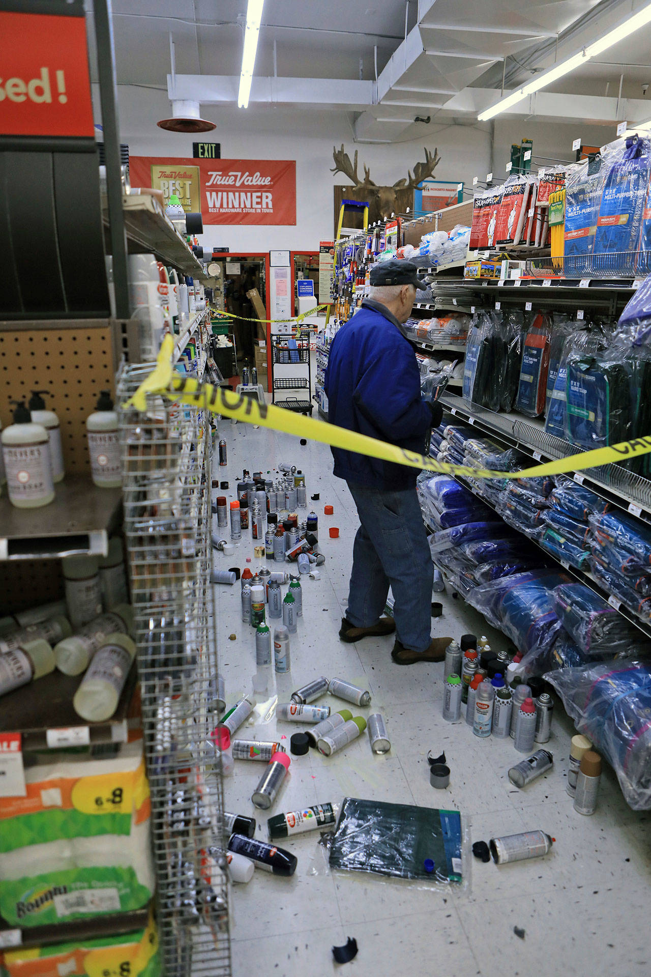 A customer at Anchorage True Value hardware store shops in the partially cleaned up paint aisle after an earthquake Friday morning in Anchorage, Alaska. Tim Craig, owner of the south Anchorage store, said no one was injured but hundreds of items hit the floor and two shelves collapsed in a stock room. (Dan Joling/The Associated Press)