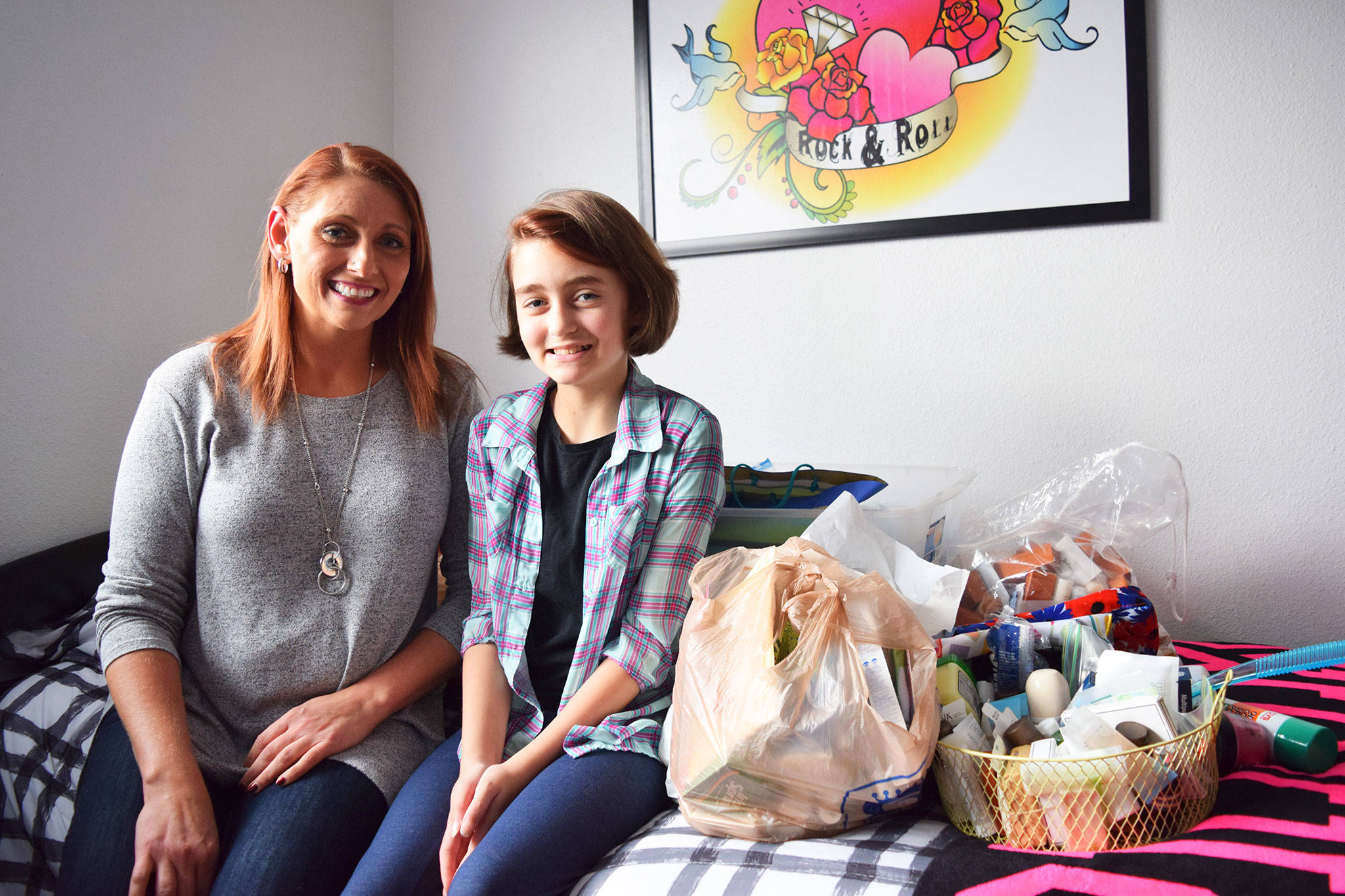 Anna Jensen, left, and her daughter River Jensen, 12, sit in their home with bags of toiletries River is collecting to donate to homeless individuals, shelters and food banks. (Erin Hawkins /Olympic Peninsula News Group)