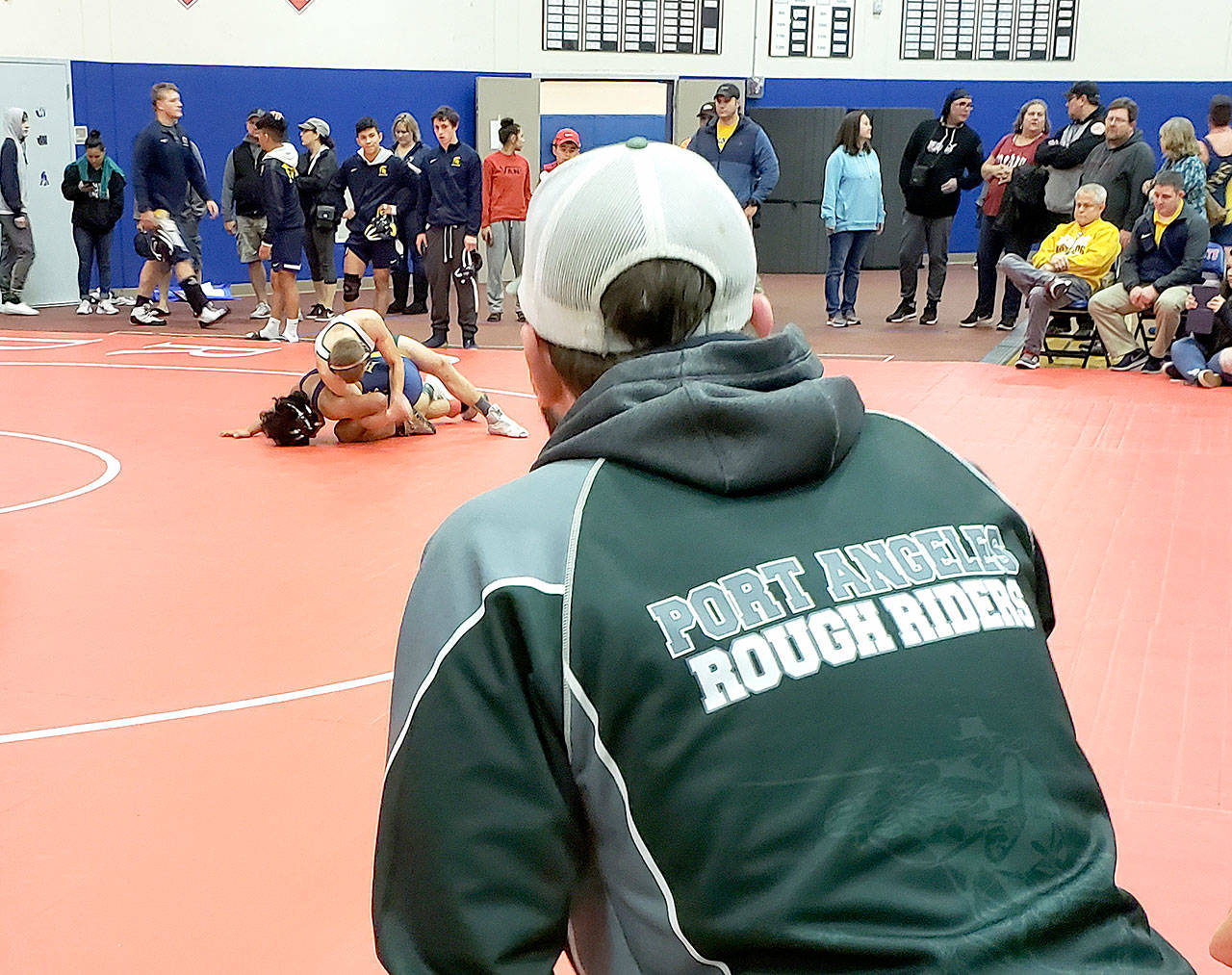 Port Angeles assistant wrestling coach Chris Myers watches as Roughrider Daniel Basden wins his 126-pound match over Josue Lucas of Forks during the Patriot Dome Classic at Washington High School on Saturday.