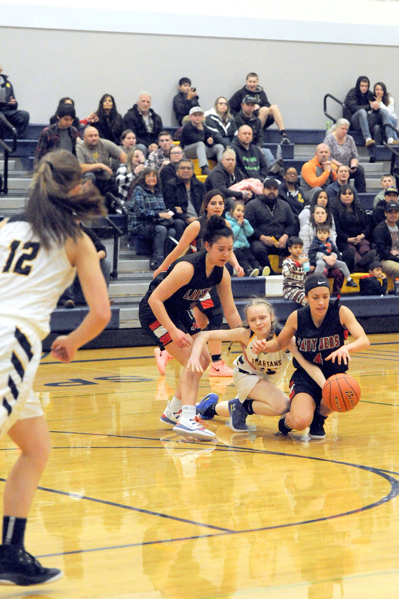 Lonnie Archibald/for Peninsula Daily News Neah Bay’s Ruth Moss (left) and Laila Greene compete with Forks’ Rylee Bouchard for control of the ball during the Red Devils’ 54-29 win over the Spartans on Wednesday.