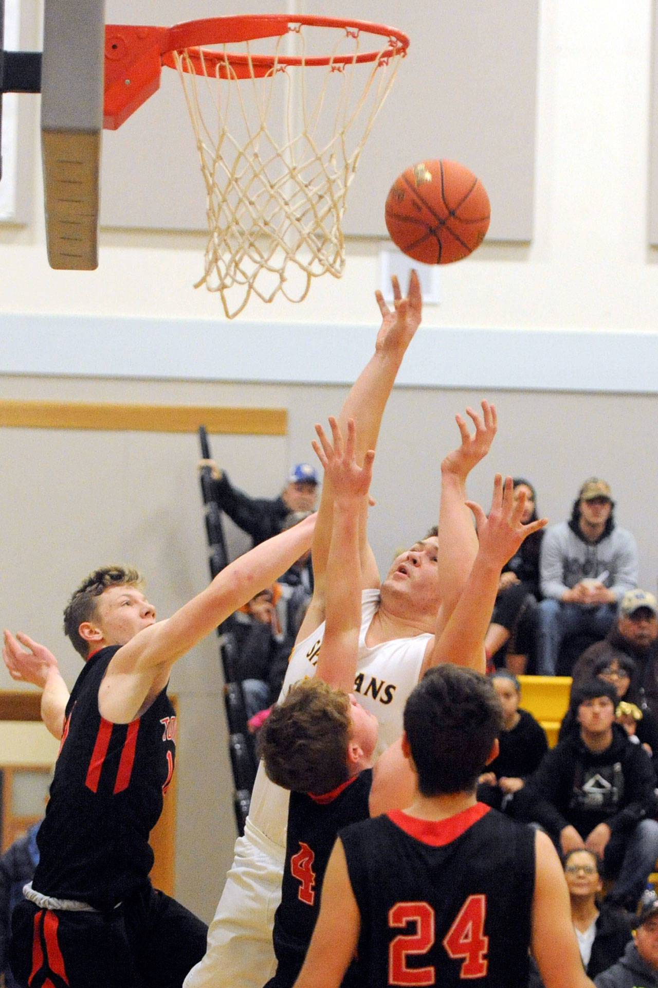 Lonnie Archibald/for Peninsula Daily News Forks’ Braton Armas scores over Port Townsend’s Cole Crawford (left), Nico Winegar and Kuba Krol during the Spartans’ 60-42 win over the Redhawks on Friday.