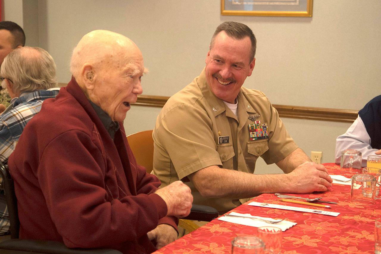 Cmdr. Rocky Pulley, commanding officer, Naval Magazine Indian Island, speaks with Roy Carter, a Navy veteran and survivor of Pearl Harbor, during a luncheon with veterans at the Sherwood Assisted Living facility. (Mass Communication Specialist 2nd Class Wyatt L. Anthony/U.S. Navy)