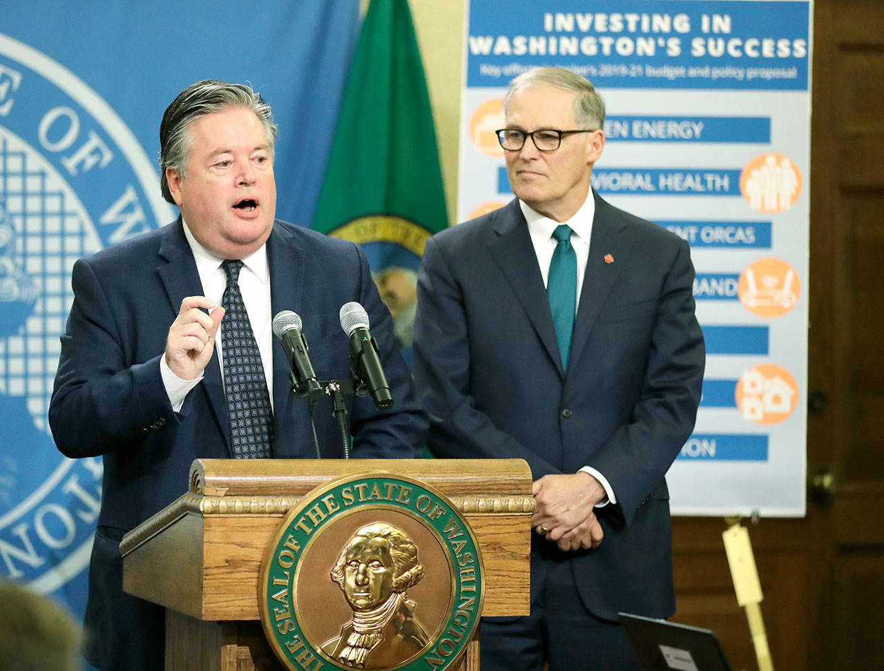 Gov. Jay Inslee, right, looks on as David Schumacher, left, director of the Office of Financial Management, talks to reporters about Inslee’s 2019-2021 budget proposal. (AP Photo/Ted S. Warren)