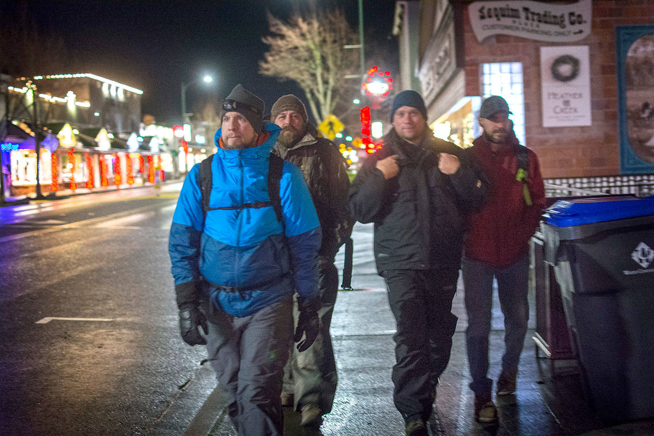 Sequim City Manager Charlie Bush, left, and three public works employees walk through downtown Sequim Tuesday night. (Jesse Major/Peninsula Daily News)