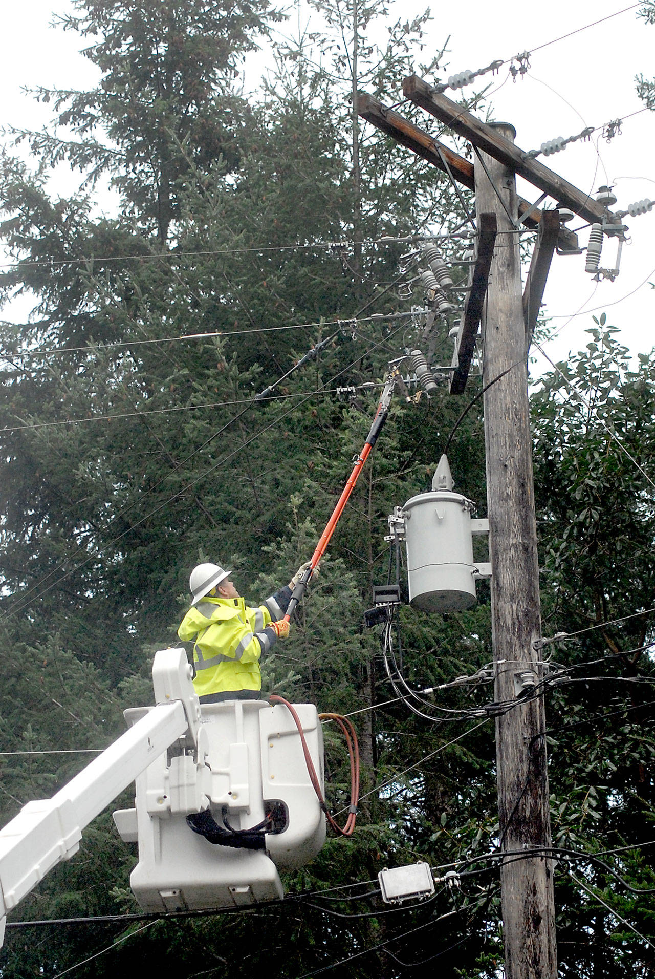 Clallam County PUD line worker Richard Christiansen works to isolate a damaged power circuit at Gasman Road at Northwood Lane that left customers in The Bluffs neighborhood east of Port Angeles without power on Thursday. (Keith Thorpe/Peninsula Daily News)