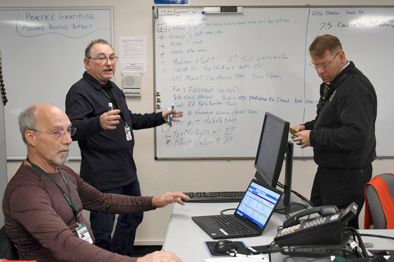Jefferson County Emergency Management kept current with all issues in the county during the storm Thursday. They were tracking problems from power outages to road blockages and wind damage. Incident Management Team (IMT) volunteer Mark Miller, left, John Crooks, Emergency Operations Center supervisor and Ted Krysinski, IMT fire representative hold a briefing on the latest issues. (Jeannie McMacken/Peninsula Daily News)