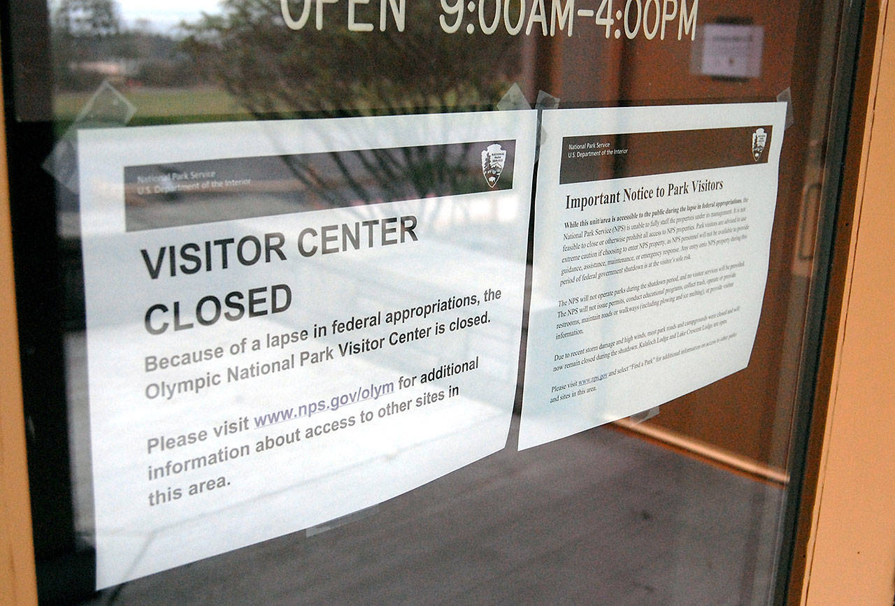 Signs on the front door of the Olympic National Park visitor center in Port Angeles explain that the park will not provide services for the duration of the government shutdown and that visitors to the park do so at their own risk. (Keith Thorpe/Peninsula Daily News)