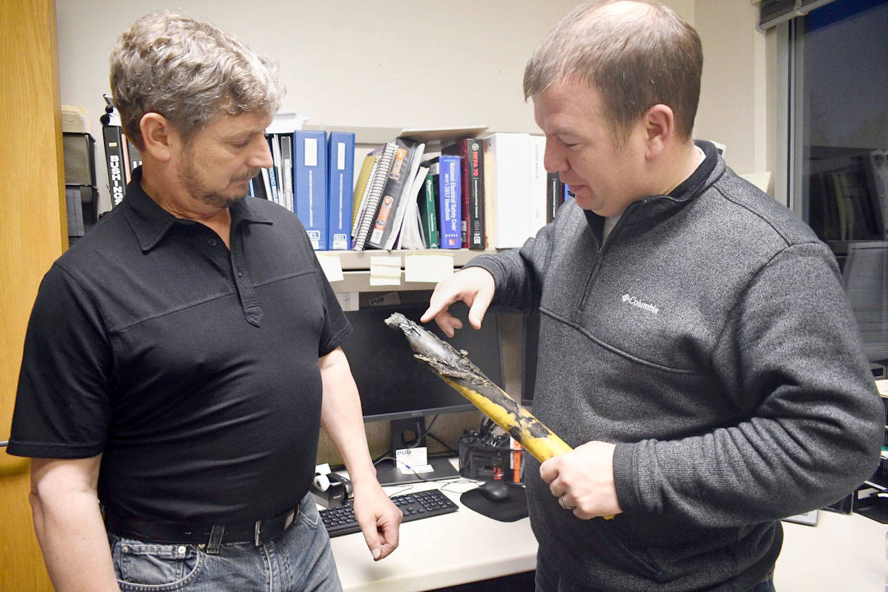Jefferson County PUD Commissioner-elect Dan Toepper, left, examines a piece of 35-year old power line that failed on Swansonville Road last week. PUD commissioners agreed to an emergency resolution authorizing work to replace all the power lines in the area and put it in conduit rather than have it directly buried. (Jeannie McMacken/ Peninsula Daily News)