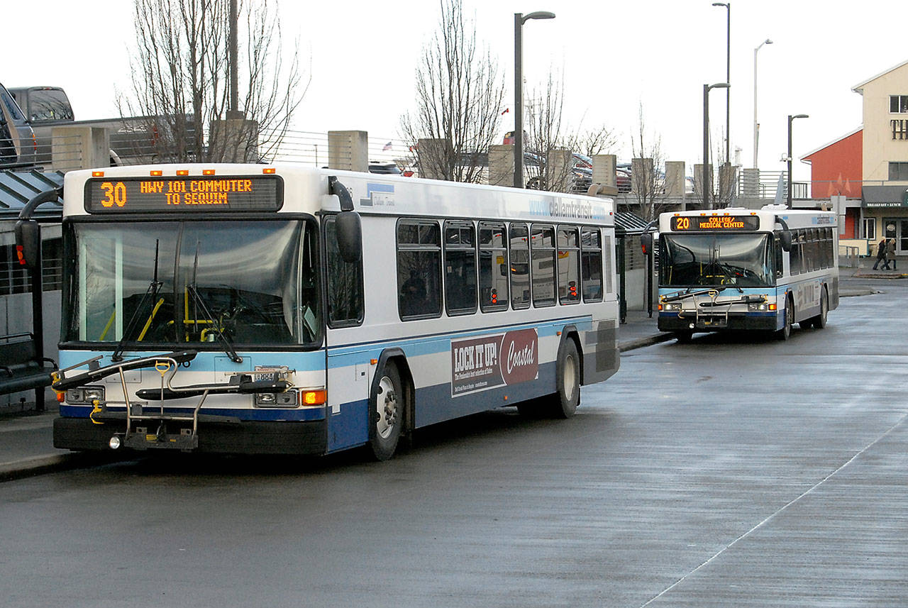 (Keith Thorpe/Peninsula Daily News) A Clallam Transit bus waits at The Gateway transit center in Port Angeles for a run to Sequim while a local bus pulls in behind it on Wednesday.