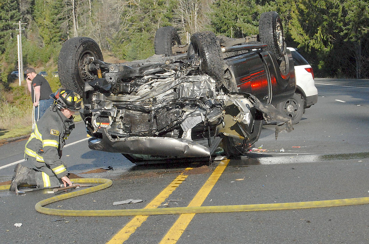 Clallam County Fire District 2 firefighter Mike Jensen works at the scene of a one-vehicle rollover wreck that temporarily closed U.S. Highway 101 at milepost 241 west of Port Angeles on Tuesday. (Keith Thorpe/Peninsula Daily News)