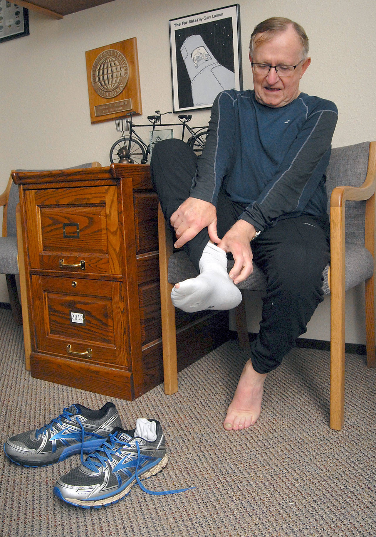 Bruce Skinner, executive director of the Olympic Medical Center Foundation, takes off his running shoes and socks after a Saturday morning warmup run in Port Angeles in preparation for running a marathon. (Keith Thorpe/Peninsula Daily News)