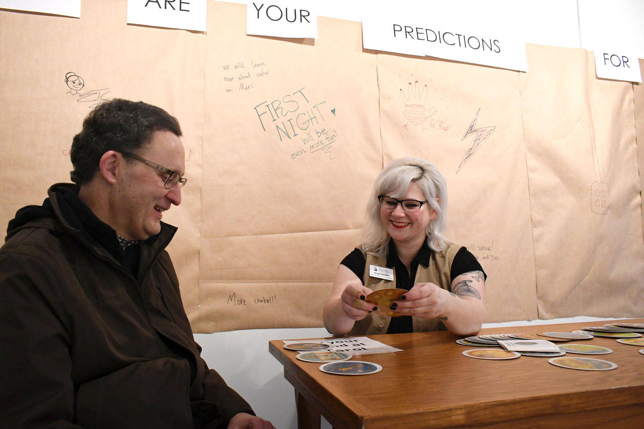 Jefferson County Historical Society Programs Manager Angie Bartlett offers to share a tarot reading with Steve Best, who was visiting from Redmond. Port Townsend’s First Night activities included a place to log predictions for the coming year. (Jeannie McMacken/Peninsula Daily News)