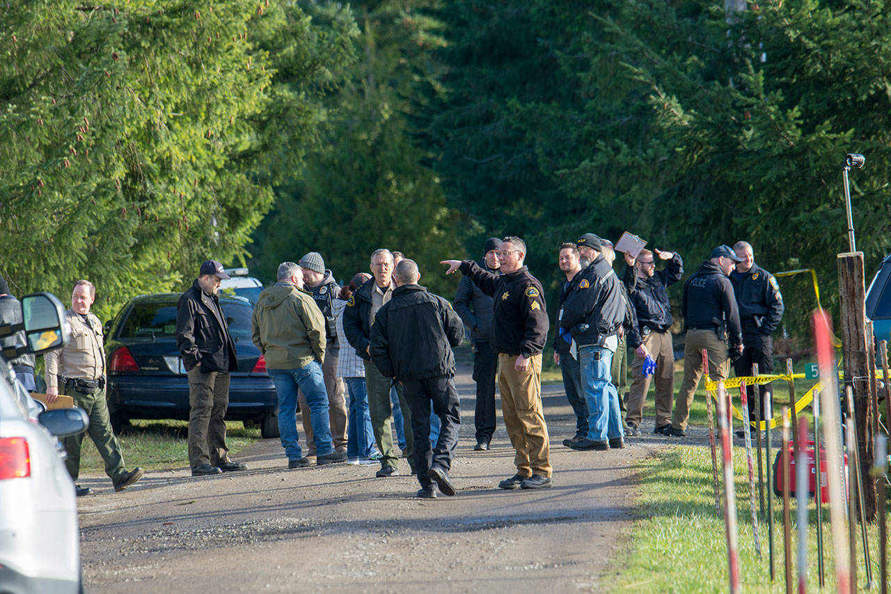 Investigators are seen Tuesday at a property on Bear Meadow Road near Port Angeles where three bodies have been found. (Jesse Major/Peninsula Daily News)