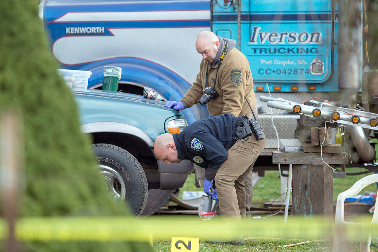 Port Angeles Police Department Detective Dave Arand and Officer Jeff Ordona look for evidence Wednesday at a home where three people were killed. (Jesse Major/Peninsula Daily News)