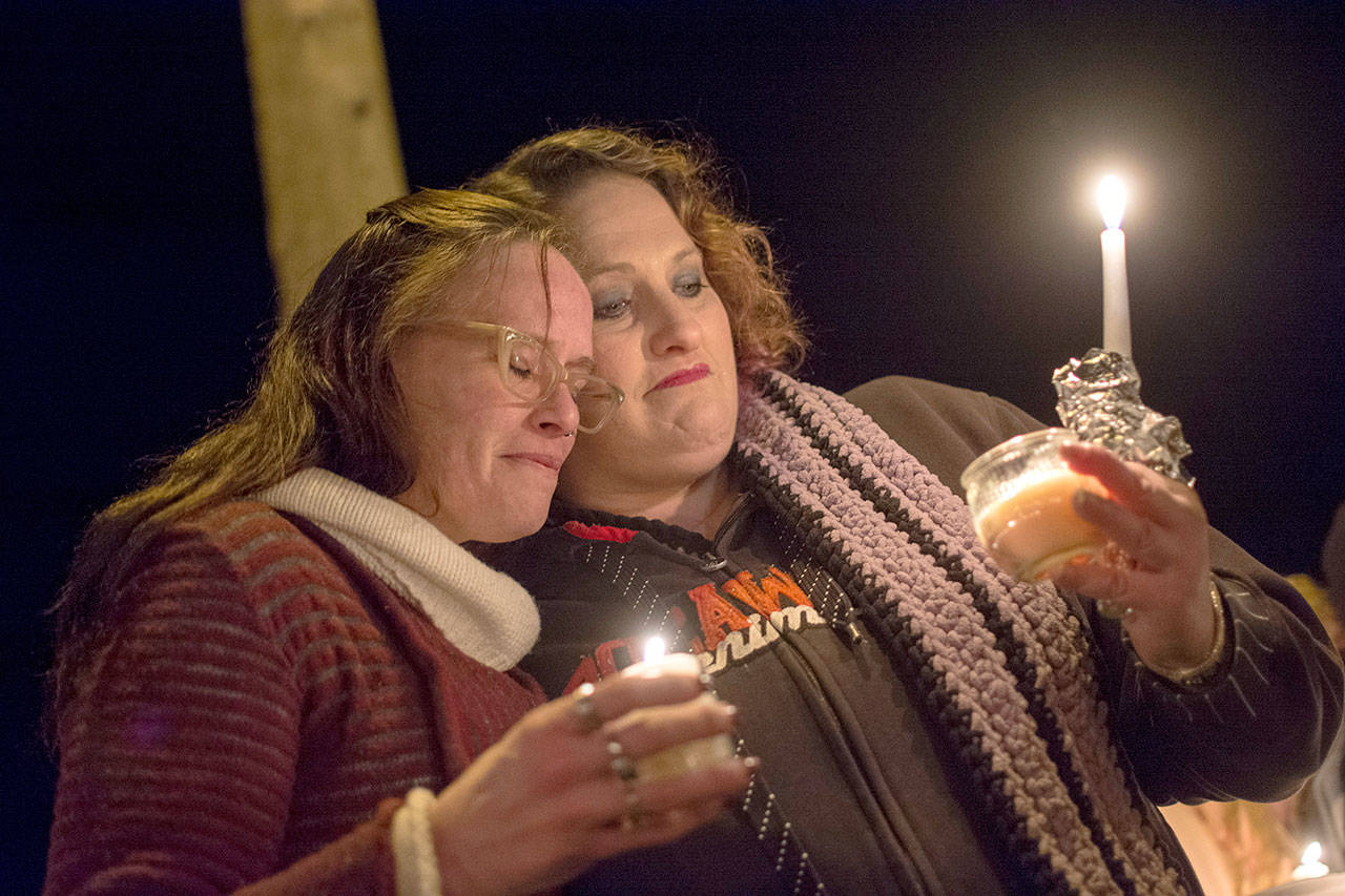 Siouxzie Hinton, left, and Jenni Tiderman embrace during a candlelight vigil Monday for Tiffany May, Jordan Iverson and Darrell Iverson. (Jesse Major/Peninsula Daily News)